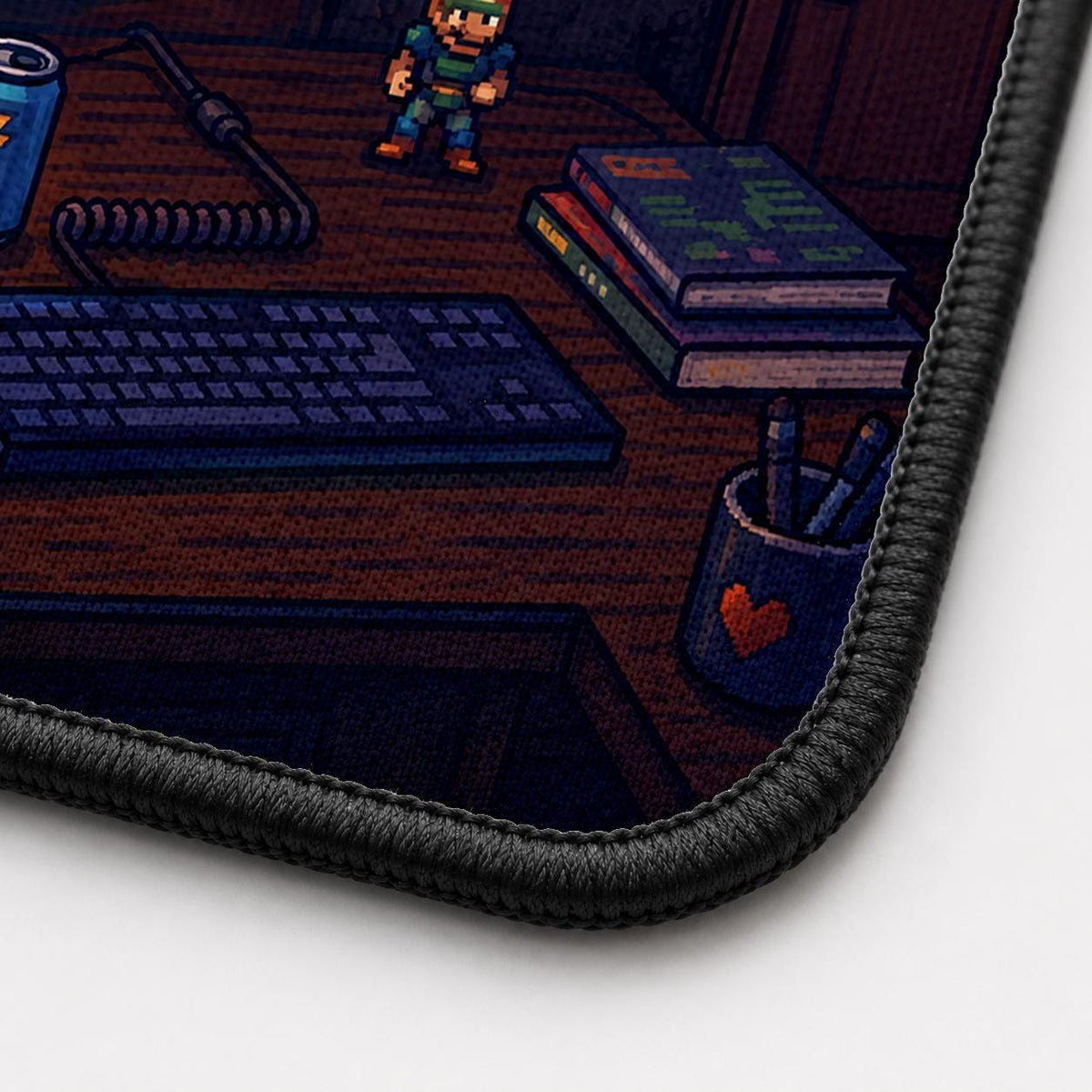 Close-up of the Retro Gamer Desktop desk mat corner showing the printed surface and the black stitched edge